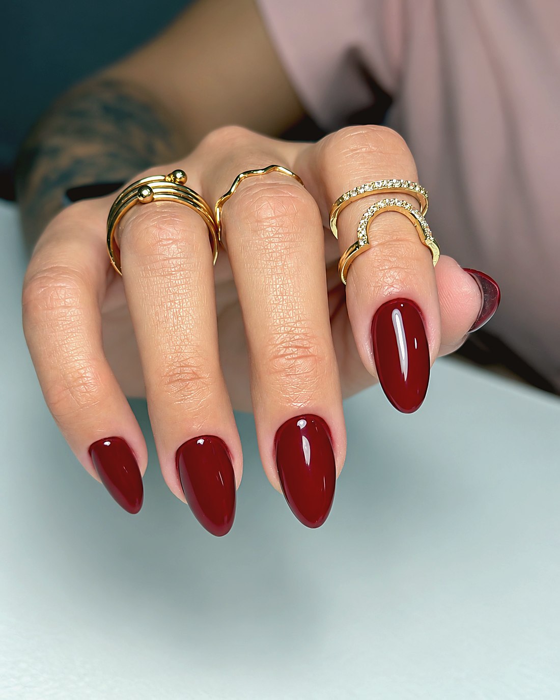 Manicura en tono vino con joyas doradas